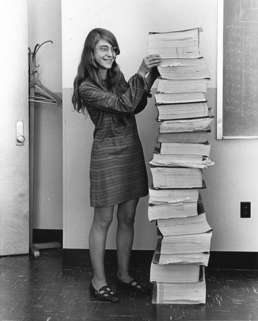 Margaret Hamilton debout à côté des listings imprimés du code source de l'ordinateur de guidage Apollo, MIT 1969