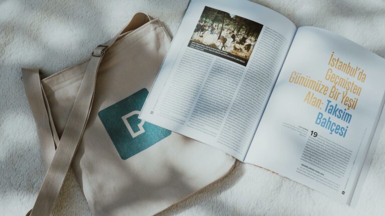 Top view of a tote bag and open magazine on a textured background with soft natural light.